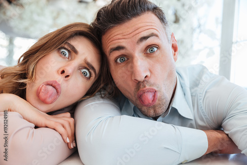 Wall Mural Happy family selfie of joyful married couple having fun together, and showing th