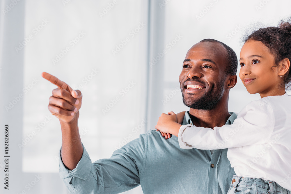 smiling african american father pointing on something to daughter smiling african american father pointing on something to daughter