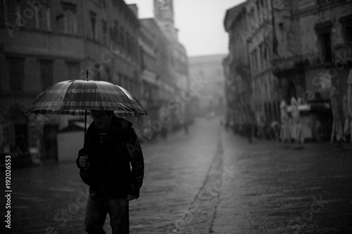 Passeggiare con ombrello sotto la pioggia in città photo