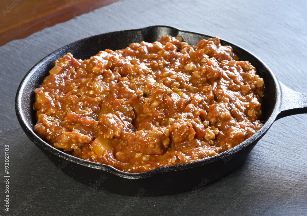 Bolognese sauce in a cooking pan or iron pan. Italian cuisine background with pasta sauce and slate plate. Bolognese sauce in a cooking pan or iron pan. Italian cuisine background with pasta sauce and slate plate.