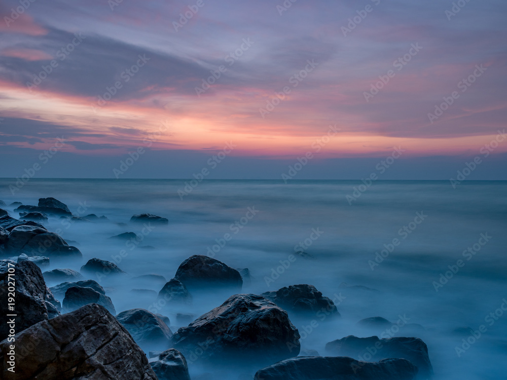 Fototapeta premium first light at the rock beach with smooth wave 