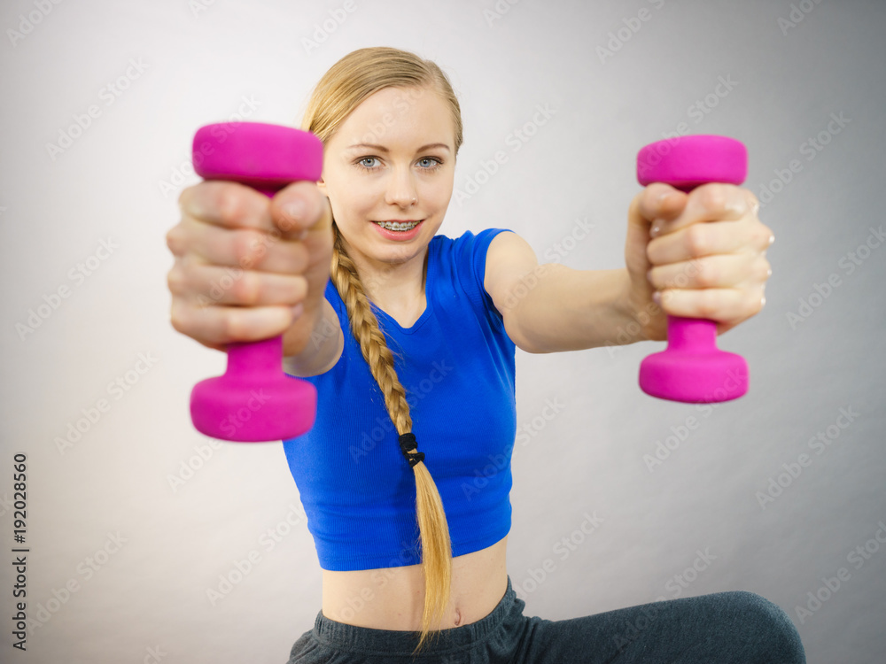 Teenage woman working out at home with dumbbell