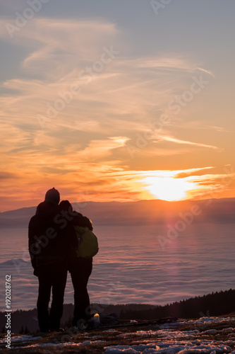 Couple on mountain looking over low stratus to beautiful sunset
