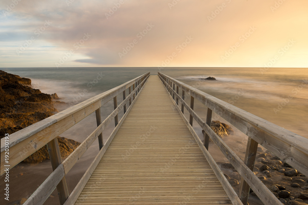 Wooden walkway in the sea at sunset