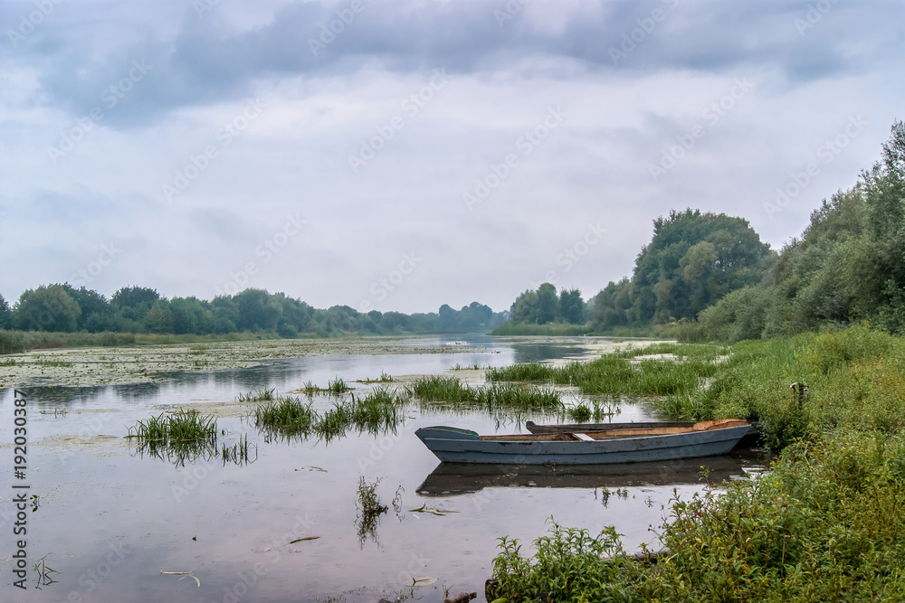 summer landscape: a river with a boat, a sky covered with clouds