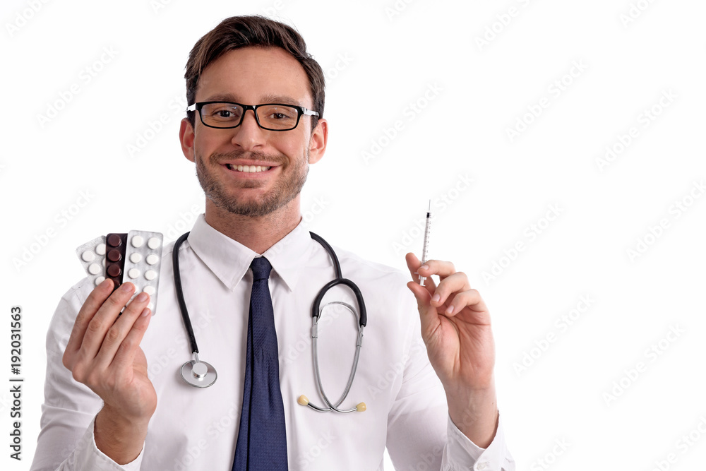 smart handsome bearded medical doctor in glasses with Stethoscope isolated on white background. Man from hospital holding syringe and a tablets in a blister pack in his hands with smile smart handsome bearded medical doctor in glasses with Stethoscope isolated on white background. Man from hospital holding syringe and a tablets in a blister pack in his hands with smile