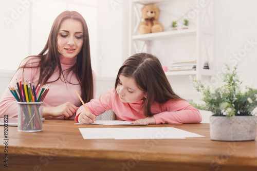 Mother helping her daughter with the homework.