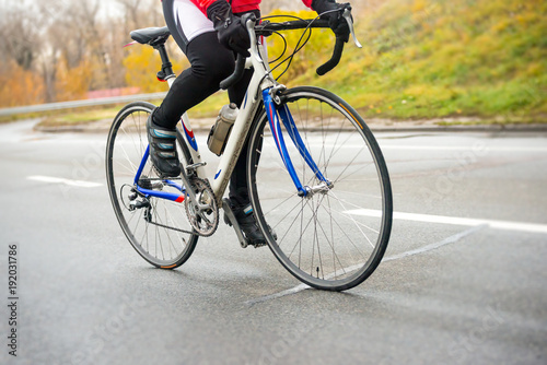 Young Woman Riding Road Bicycle on the Highway in the Cold Autumn Day. Healthy Lifestyle.