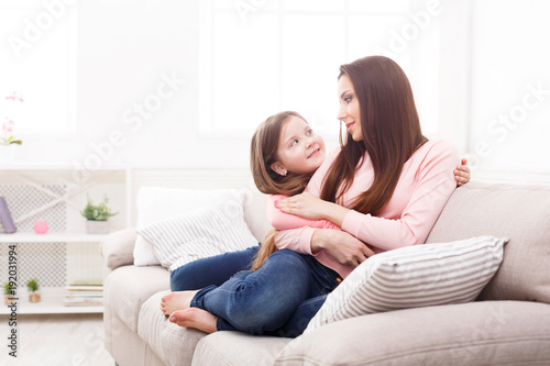 Mother with her cute little daughter sitting on the sofa.