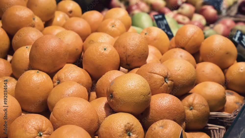Young woman picking out fruit in supermarket. Woman choosing fresh oranges in grocery store. Close-up. Young woman picking out fruit in supermarket. Woman choosing fresh oranges in grocery store. Close-up.