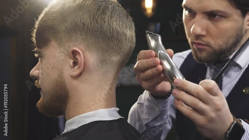 Cropped close up of a handsome professional barber working at his barbership using electrical clipper or trimmer styling hair of his male client service occuaption profession job worker masculine. photo