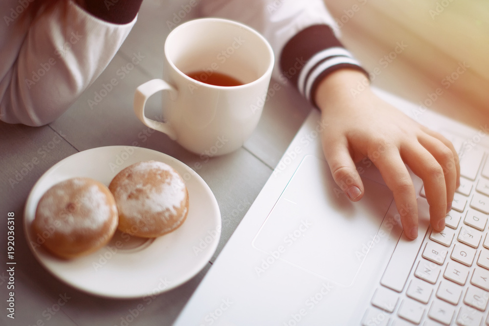 Laptop, hand, cup and plate with cookes on table Laptop, hand, cup and plate with cookes on table