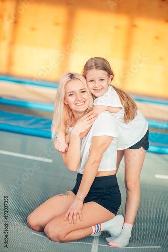 pretty siters girls having fun indoor. Sitting on trampoline in children zone photo