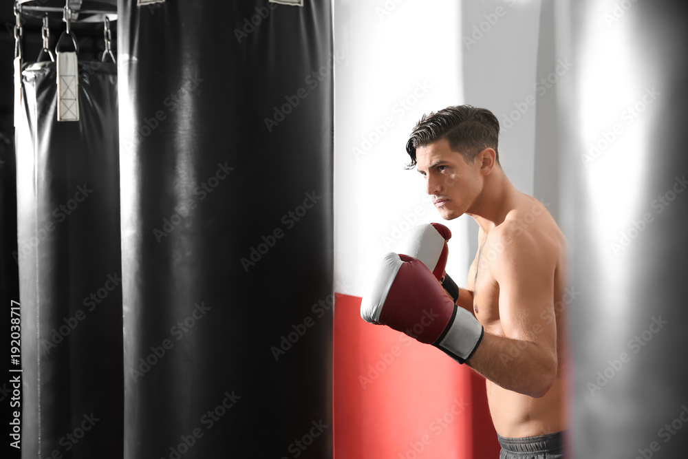 Male boxer training with punching bag in gym