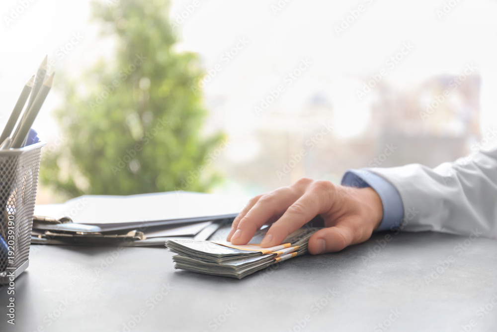 Fototapeta premium Doctor with bribe at workplace, closeup