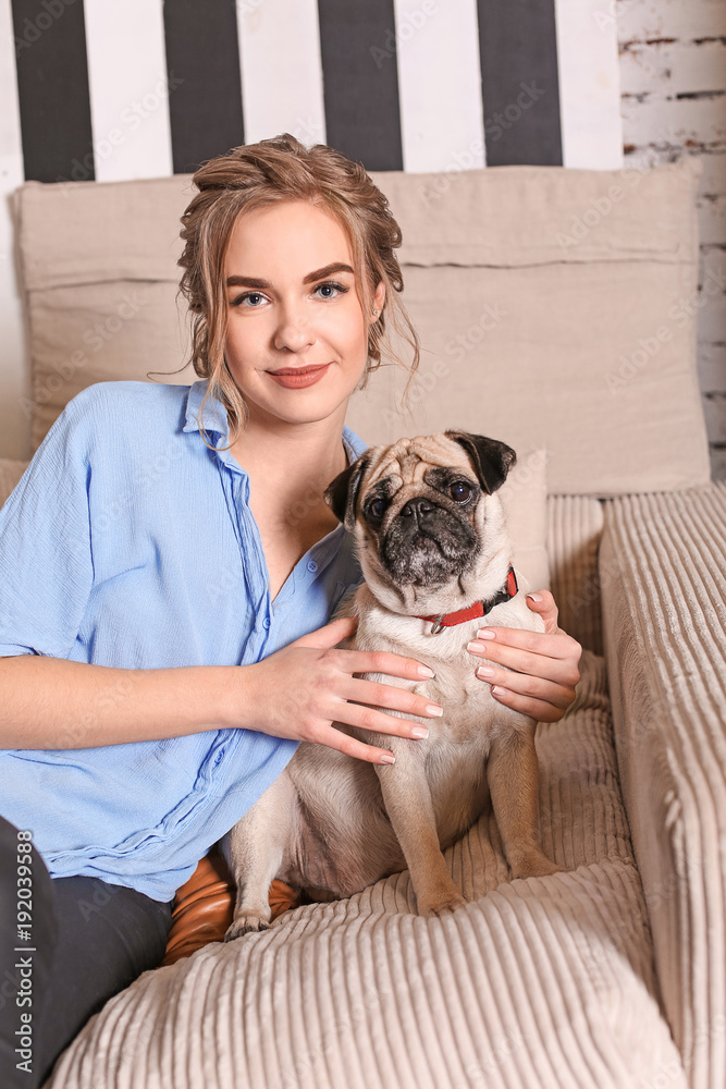 Young woman with cute pug dog on sofa at home. Pet adoption Young woman with cute pug dog on sofa at home. Pet adoption