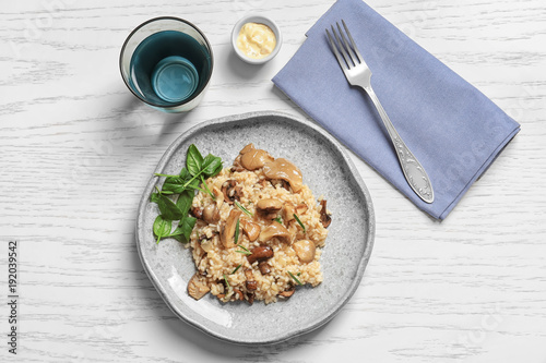 Plate with delicious risotto and mushrooms on table