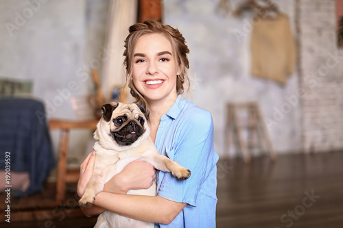 Young woman with cute pug d...
