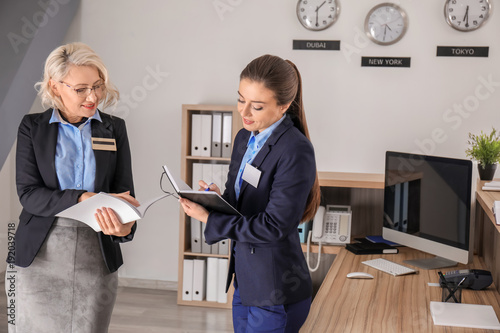 Female receptionist teaching trainee in hotel
