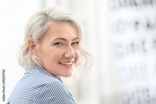 Mature woman with hearing aid indoors photo