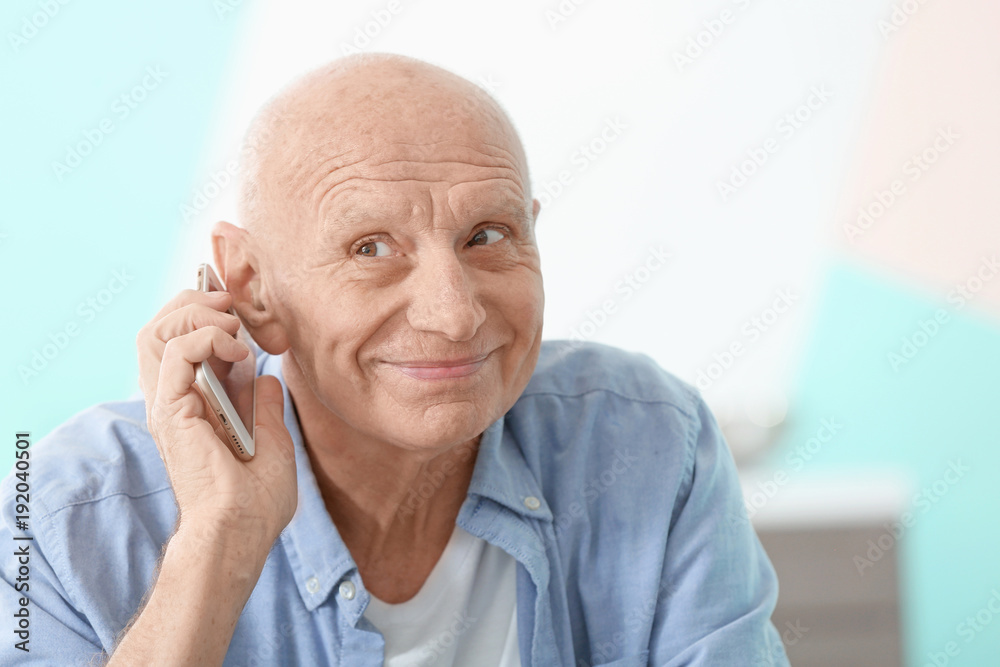 Hearing impaired man talking on phone at home Hearing impaired man talking on phone at home
