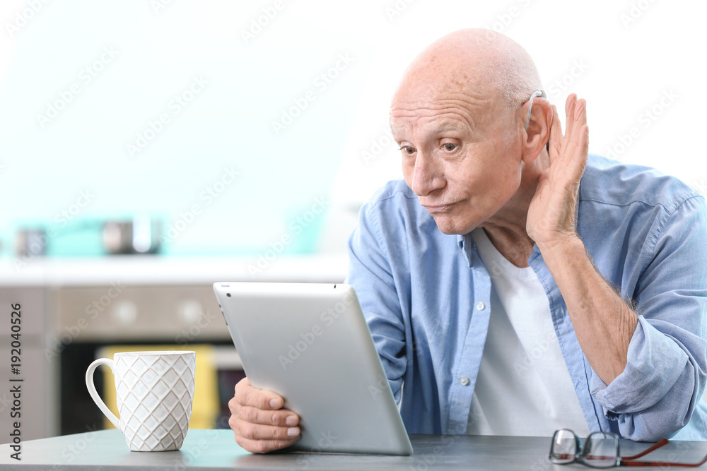 Hearing impaired man with tablet at home Hearing impaired man with tablet at home