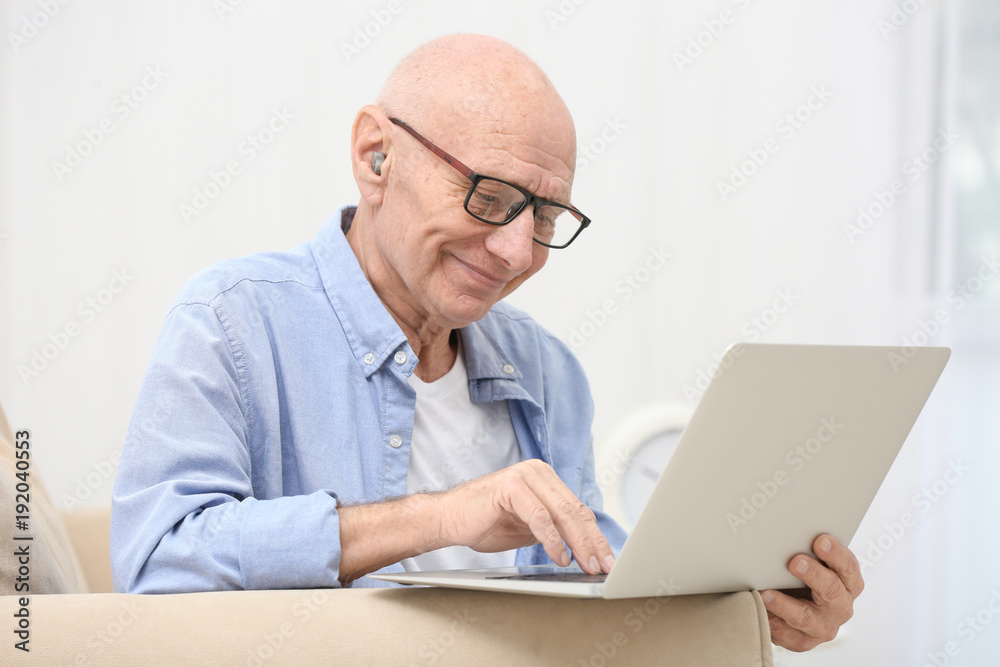 Hearing impaired man working with laptop at home Hearing impaired man working with laptop at home