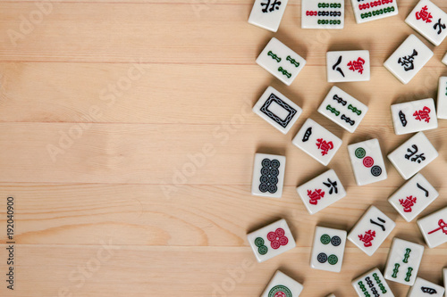White-green tiles for mahjong on a brown wooden background. Empty space on the left photo