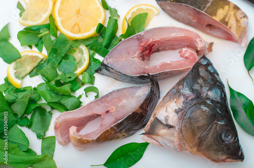 Raw fish with greens on a white cutting board photo