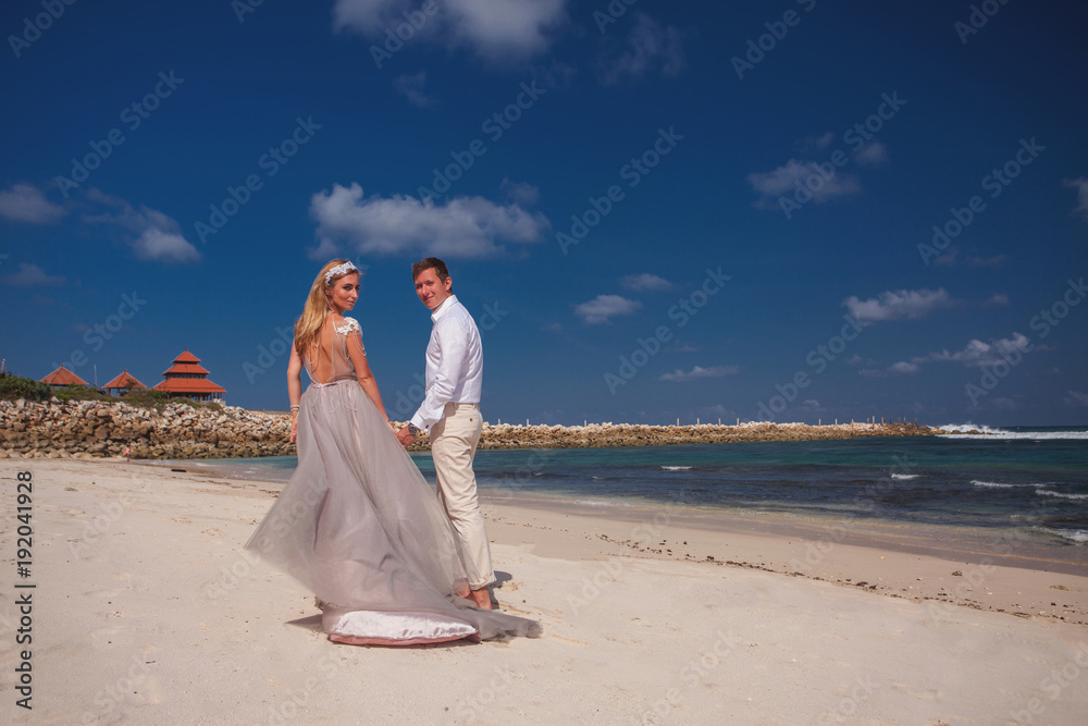 Wedding couple just married holds hands and walking at beach Wedding couple just married holds hands and walking at beach