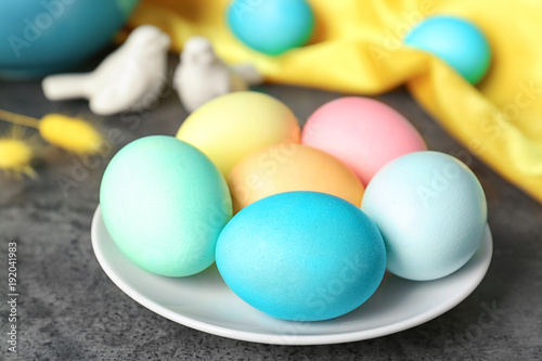 Plate with colorful Easter eggs on table