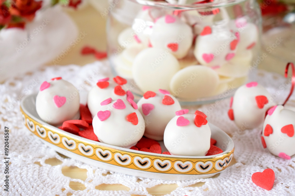 White chocolate sweets and cake pops decorated with little confectionery hearts White chocolate sweets and cake pops decorated with little confectionery hearts