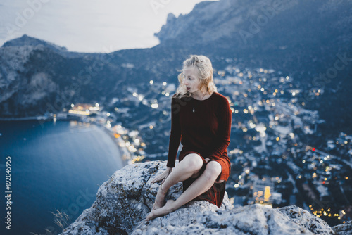 Caucasian woman sitting on rock near ocean