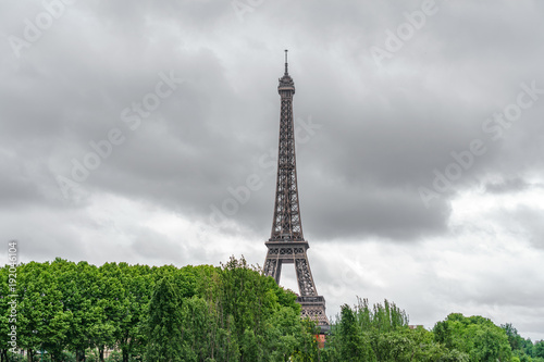 The Eiffel Tower emerging over trees with stormy clouds © F.C.G.