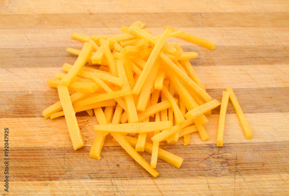 Cheddar cheese slices on wooden board