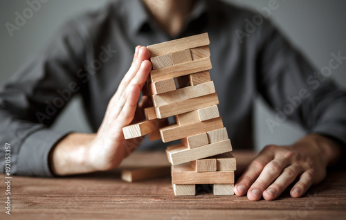 Businessman holds the model of business, made from wood blocks. Alternative risk concept, business plan and business strategy. Insurance concept. photo