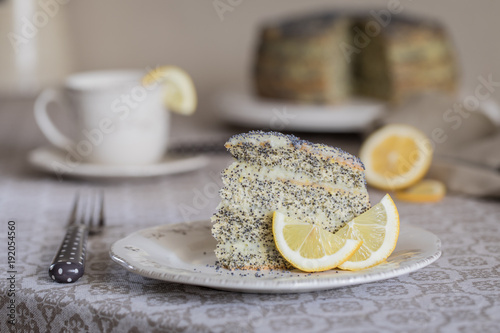 A piece of Cake with poppy seeds and lemon cream and a cup of tea photo