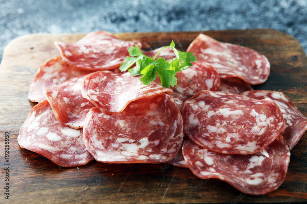 thinly sliced salami on a wooden texture on the background. thinly sliced salami on a wooden texture on the background.