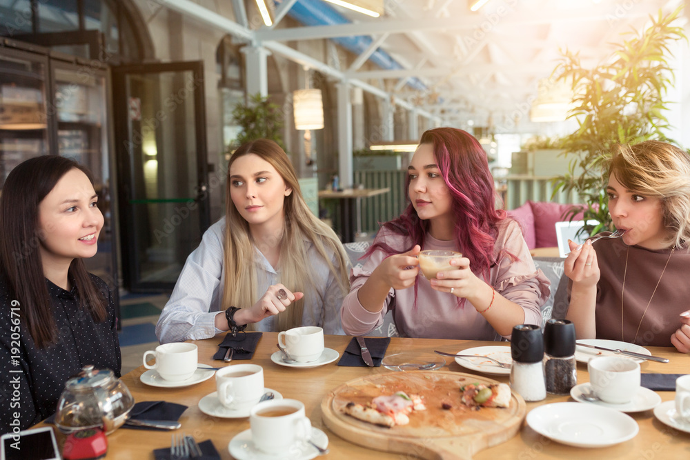 Gossipgirls, freindship concept. Female friends with tea and coffee speaking in cafe, gossip and news. Smiling women laughing, talking and smiling together in coffee shop