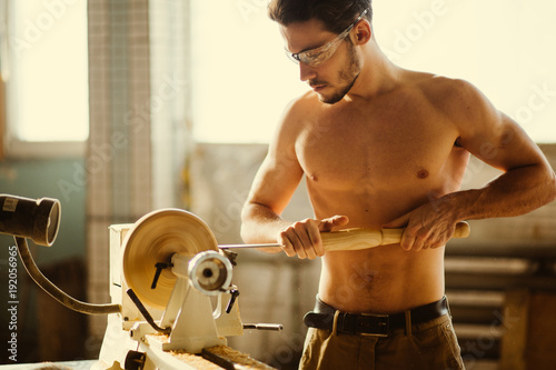 Wood lathe .The naked Carpenter lathing wood to make product photo
