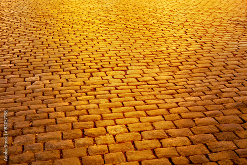Golden light on street paving blocks made of rectangular stone. Night photo 