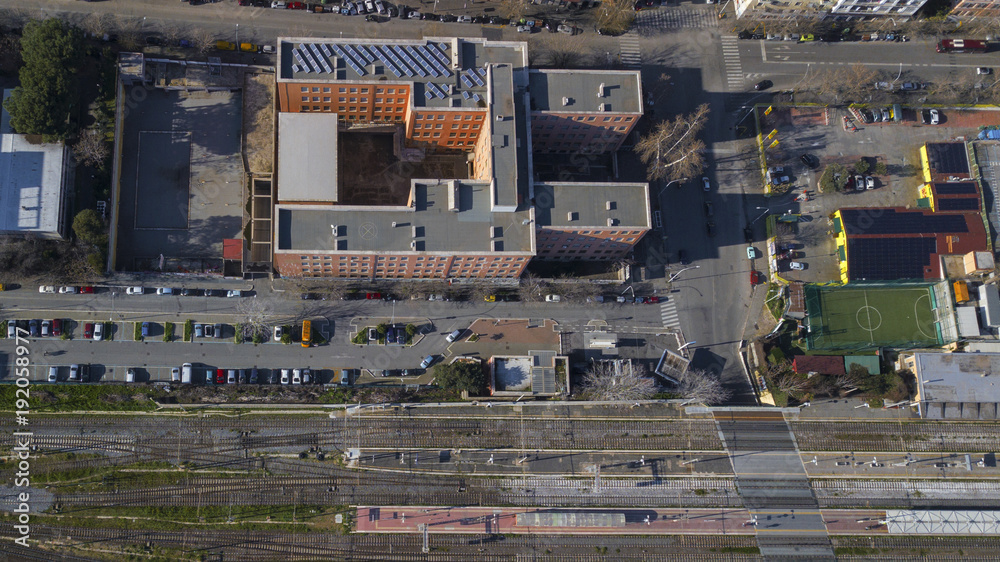  Perpendicular aerial view of a square orange building located in Rome, Italy. Around the building there are streets where there are parked cars and planted trees.