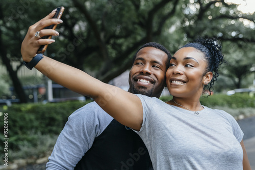 Smiling Black couple posing for cell phone selfie photo