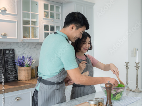 happy young couple have fun in modern kitchen indoor while preparing fresh fruits and vegetables food salad,Couple Cooking Hobby Lifestyle Concept,.Smiling young couple cooking food in the kitchen,