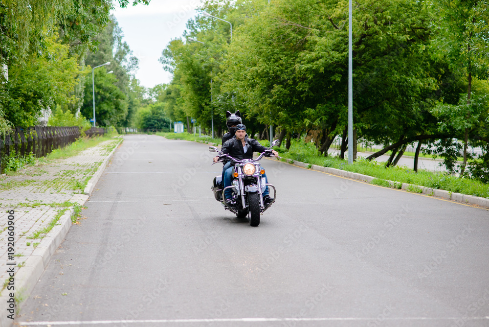 A man and a woman ride a motorbike on the road.