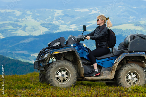Excited young woman on quad bike. Happy young woman driving all terrain vehicle in nature.