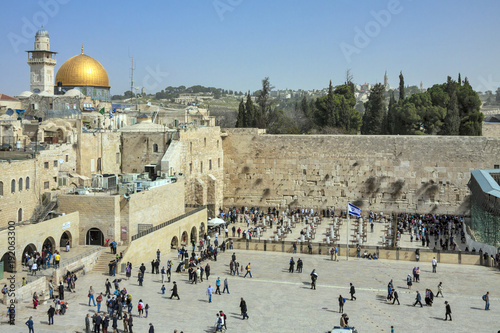 Israel - Jerusalem - Jewish people going and praying at the wailing wall with cupola of Dome of the Rock on background