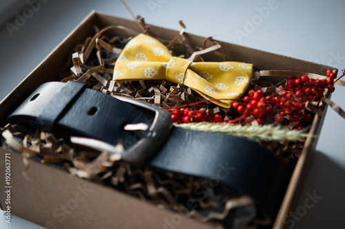 Fototapeta Naklejka Na Ścianę i Meble -  Красивые подарки, ремень и галстук бабочка / крафтовые подарки и яркое наполнение, подарочные наборы