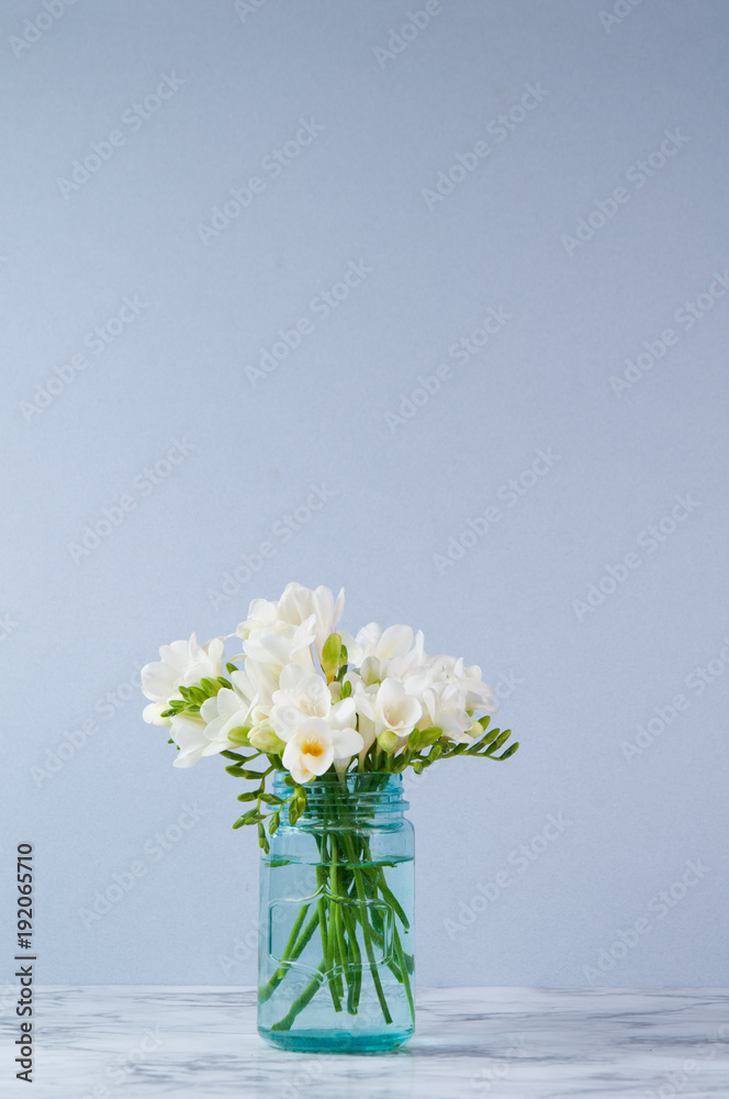 white fressia flowers in a blue jar