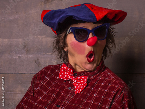 Woman funny clown with red nose and blue sunglasses. Comedy concept.